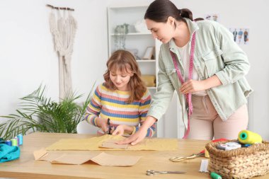 Atölyede kumaş kesen kadın terziler.