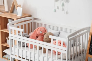 Beyaz duvarın yanında rafları olan şirin oyuncaklar.