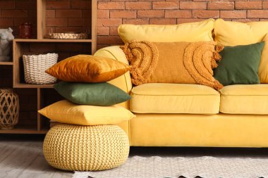 Sarı kanepeli, yastıklı ve raf üniteli oturma odasının içi.