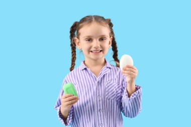 Mavi arka planda sabun çubukları olan küçük kız.