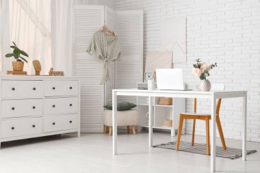 Modern dizüstü bilgisayarı ve hafif ev ofisinde güzel çiçekleri olan şık çalışma alanı.