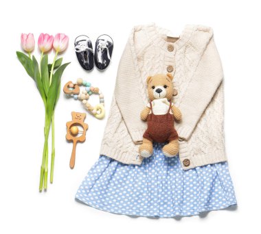 Beyaz arka planda oyuncakları ve laleleri olan küçük bir bahar kıyafeti.