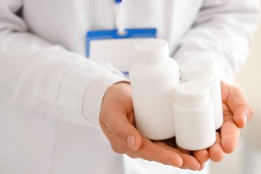 Ofisinde ilaç şişeleri olan erkek doktor, yakın plan.