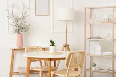 Mutfağın içinde raf ünitesi ve masa üzerindeki vazolarda çiçek açan dallar.