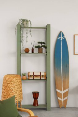 Oturma odasının içinde sörf tahtası ve raf ünitesi var.