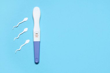 Mavi arka planda sperm hücreleri ve hamilelik testi