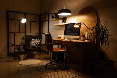 Programcının çalışma yeri, koltuğu ve parlak lambaları olan karanlık ofisin içi.