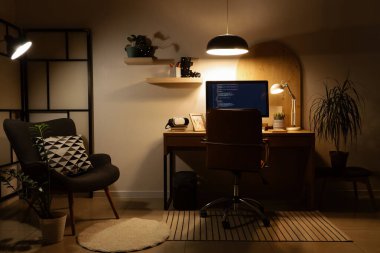 Programcının çalışma yeri, koltuğu ve parlak lambaları olan karanlık ofisin içi.