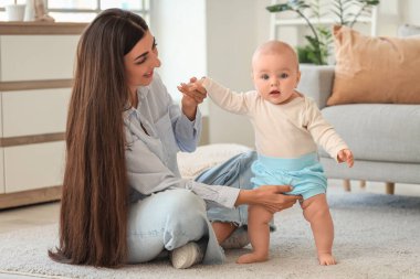 Genç, mutlu bir anne ve tatlı küçük kızı evde yerde oturuyor.