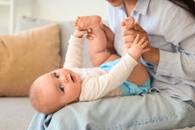 Genç anne evdeki kanepede tatlı küçük kızıyla eğleniyor.