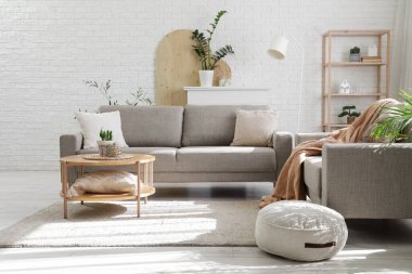 Rahat gri koltukları, kahve masası ve çiçekleri olan şık bir oturma odası.