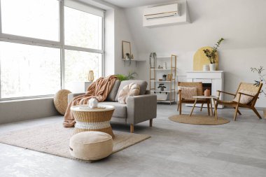 Rahat gri kanepesi, kahve masası, puf ve çiçekleri olan şık bir oturma odası.