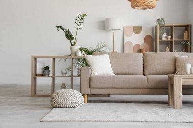 Rahat gri kanepesi, sehpası ve çiçekleri olan şık bir oturma odası.