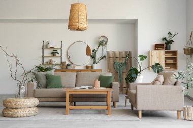 Rahat gri koltukları, kahve masası ve çiçekleri olan şık bir oturma odası.