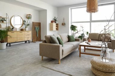 Rahat gri koltukları, kahve masası ve çiçekleri olan şık bir oturma odası.