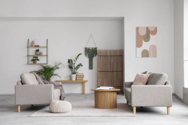 Rahat gri koltukları, kahve masası ve çiçekleri olan şık bir oturma odası.