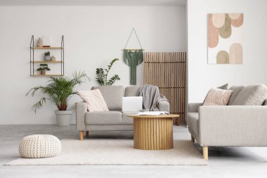 Rahat gri koltukları, kahve masası ve dizüstü bilgisayarı olan şık bir oturma odası.