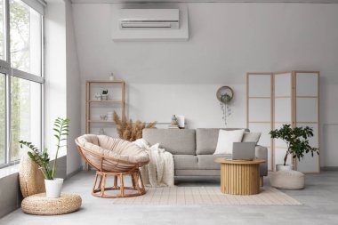 Kahve masasında rahat gri kanepesi, koltuğu ve dizüstü bilgisayarı olan şık bir oturma odası.