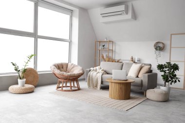 Kahve masasında rahat gri kanepesi, koltuğu ve dizüstü bilgisayarı olan şık bir oturma odası.