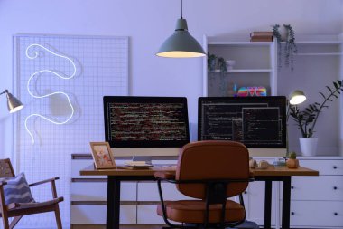 Ofiste bilgisayar monitörlü ve parlayan lambalı programcı masası