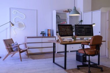 Programcının masası, koltuğu ve parlayan lambaları olan ofis içi