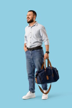 Mavi arka planda spor çantalı genç adam.