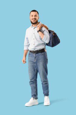 Mavi arka planda spor çantalı genç adam.