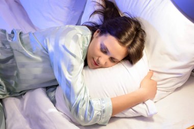 Yatak odasında yastıkların üzerinde uyuyan genç bir kadın.