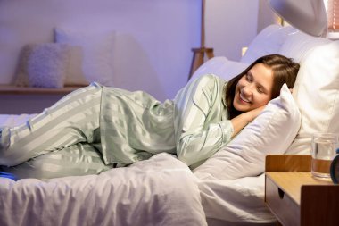 Yatak odasında yastıkların üzerinde yatan genç bir kadın.