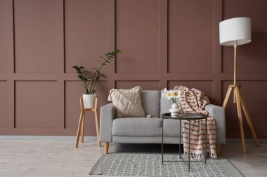 İçinde kanepe, lamba ve vazoda papatya olan oturma odası.