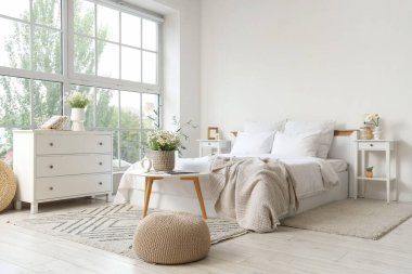 Masalar ve vazolarda papatyalar olan aydınlık yatak odasının içi.