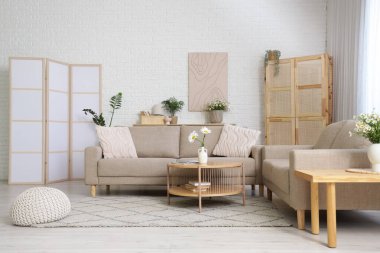 Oturma odasının içinde vazolarda kanepeler, masalar ve papatyalar var.