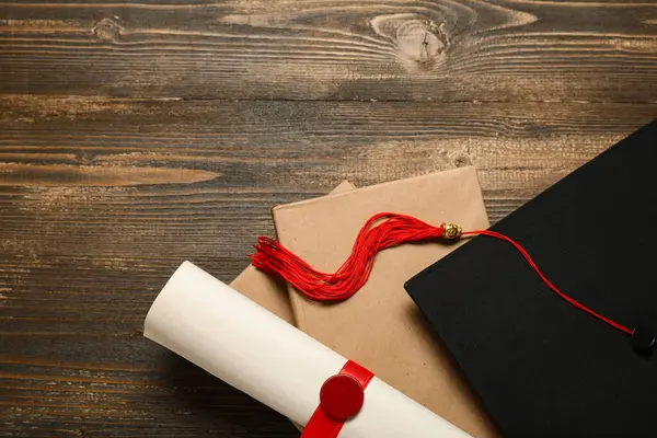 Mezuniyet şapkası, kitaplar ve ahşap arka plan diploması.