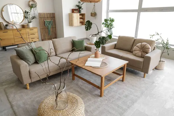 Rahat gri koltukları, kahve masası ve çiçekleri olan şık bir oturma odası.