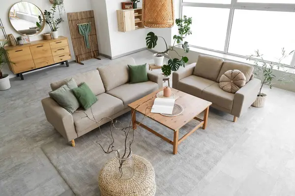 Rahat gri koltukları, kahve masası ve çiçekleri olan şık bir oturma odası.