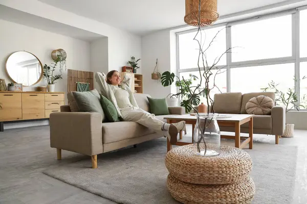 Rahat gri koltukları, kahve masası ve çiçekleri olan şık bir oturma odası.