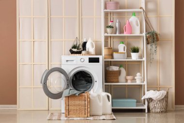 Çamaşır odasının içinde katlanan perde, çamaşır makinesi ve raf ünitesi var.