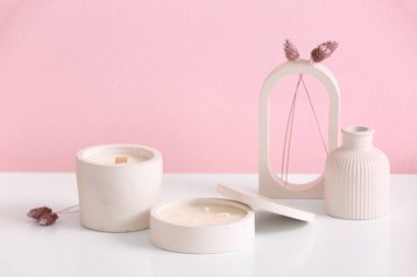 Odadaki pembe duvarın yanındaki masada elinde mumlar ve dekor olan tutucular.