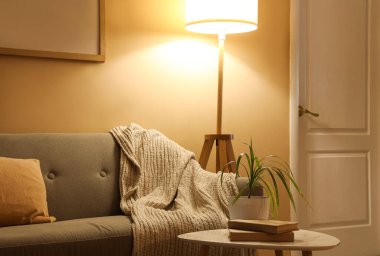 Gri kanepeli, sehpalı ve akşamları parlayan standart lambalı şık bir oturma odası.