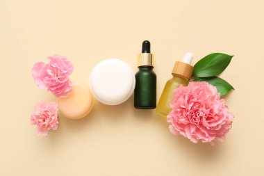 Bej arka planda farklı kozmetik ürünleri ve güzel çiçekler