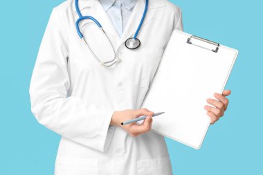 Steteskoplu kadın kardiyolog mavi arka plandaki panoya bakıyor, yakın plan.