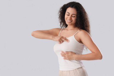 Genç Afro-Amerikalı kadın göğsünü açık arka planda kontrol ediyor. Kanser farkındalığı kavramı