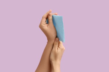 Eflatun arka planda mavi kağıt peçeteli kadın elleri