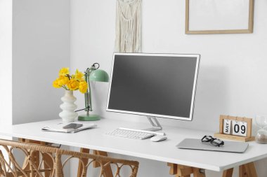 Boş bilgisayar monitörü ve ışık ofisindeki masasında çiçekler olan vazo.