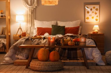 Sonbahar süslemeleri ve akşamları mumları olan şık bir yatak odası.