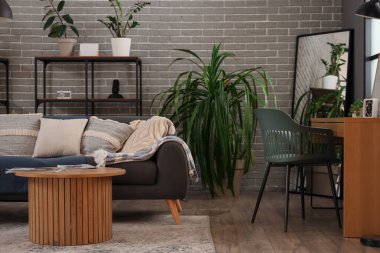 Kanepesi, masası ve palmiyesi olan modern oturma odasının içinde.