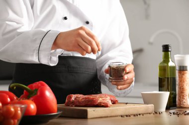 Mutfaktaki masada çiğ et yiyen erkek şef, yakın plan.