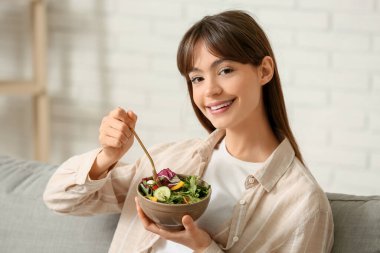 Genç kadın evde taze sebze salatası yemek