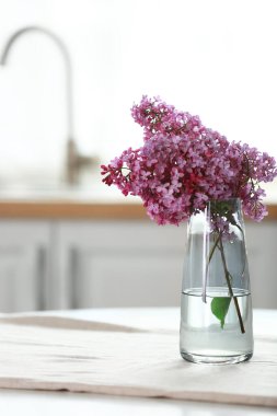 Mutfaktaki masada leylak çiçekli vazo.