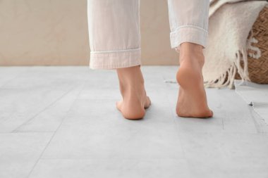 Çıplak ayaklı kadın yatak odasında ısıtmayla yerde yürüyor.